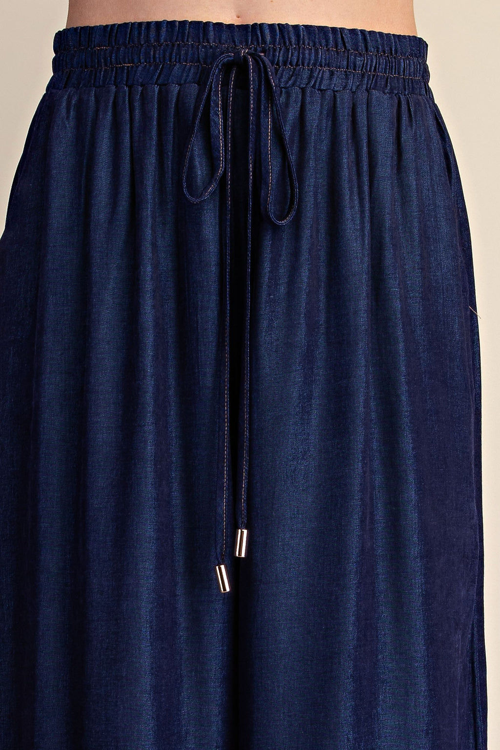 Close-up of a person wearing dark navy blue drawstring pants, showing the elastic waistband and fabric texture against a plain light background.