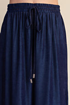Close-up of a person wearing dark navy blue drawstring pants, showing the elastic waistband and fabric texture against a plain light background.